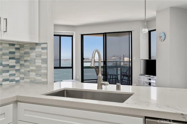 1310 E Ocean Blvd Unit 1103, Long Beach, CA 90802 - kitchen featuring a sink, white cabinets, backsplash, light stone countertops, and hanging light fixtures