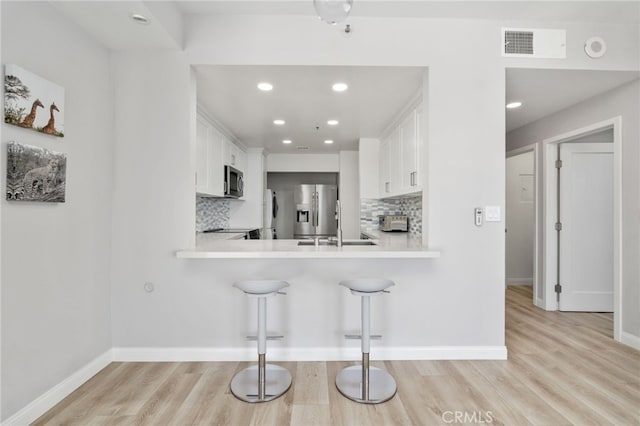 1310 E Ocean Blvd Unit 1103, Long Beach, CA 90802 - kitchen with appliances with stainless steel finishes, decorative backsplash, light wood-style flooring, light countertops, and white cabinets