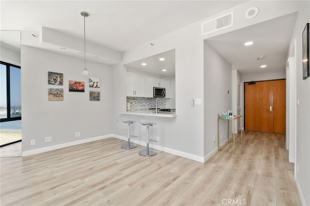 1310 E Ocean Blvd Unit 1103, Long Beach, CA 90802 - kitchen featuring stainless steel microwave, light wood-type flooring, recessed lighting, white cabinets, and light countertops