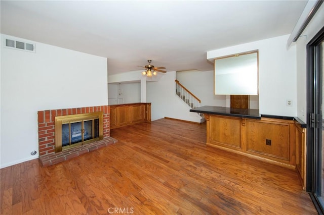 2440 Chandler Ave Unit 4, Simi Valley, CA 93065 - unfurnished living room with wood finished floors, stairs, a ceiling fan, and a brick fireplace