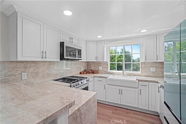 308 S Cabrillo Ave Unit 3, San Pedro, CA 90731 - kitchen with stainless steel appliances, a sink, white cabinets, light wood finished floors, and tasteful backsplash