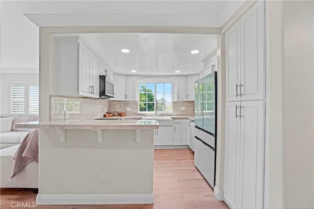 308 S Cabrillo Ave Unit 3, San Pedro, CA 90731 - kitchen with a peninsula, high quality fridge, stainless steel microwave, light wood-type flooring, and a breakfast bar