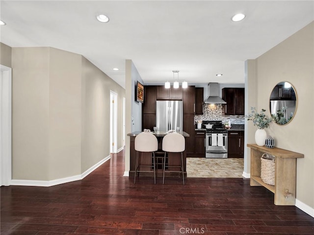 10404 Gaviota Ave, Granada Hills, CA 91344 - kitchen featuring stainless steel appliances, dark wood finished floors, wall chimney range hood, dark brown cabinets, and a kitchen bar
