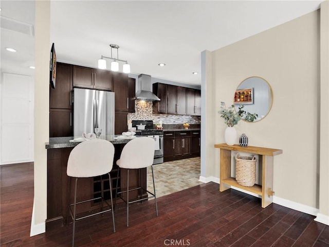 10404 Gaviota Ave, Granada Hills, CA 91344 - kitchen with appliances with stainless steel finishes, wall chimney exhaust hood, dark brown cabinetry, a breakfast bar area, and dark wood-style floors