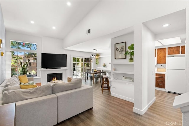 2342 Aspen St, Tustin, CA 92782 - living area with light wood-style flooring, a lit fireplace, recessed lighting, high vaulted ceiling, and baseboards