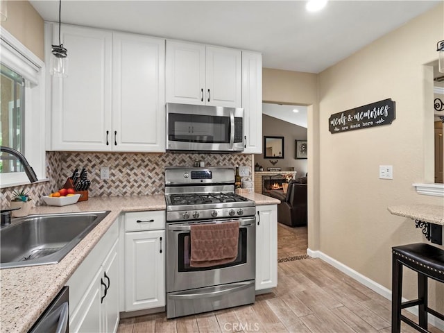 15242 Poppy Meadow St, Canyon Country, CA 91387 - kitchen with stainless steel appliances, a sink, tasteful backsplash, light wood finished floors, and baseboards