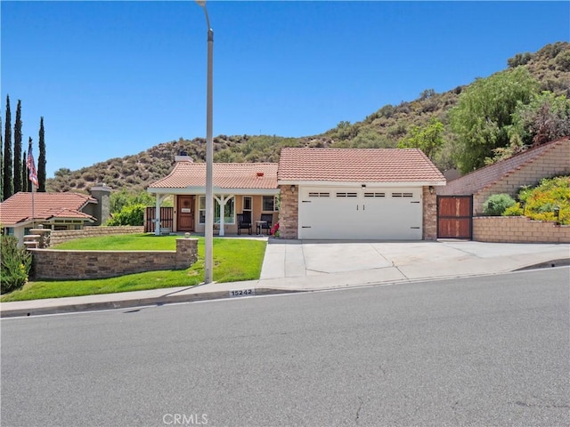 15242 Poppy Meadow St, Canyon Country, CA 91387 - view of front facade with a mountain view, an attached garage, a tiled roof, concrete driveway, and a chimney