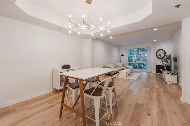 585 N Rossmore Ave Unit 209, Los Angeles, CA 90004 - dining space with light wood finished floors, a raised ceiling, baseboards, a warm lit fireplace, and a chandelier