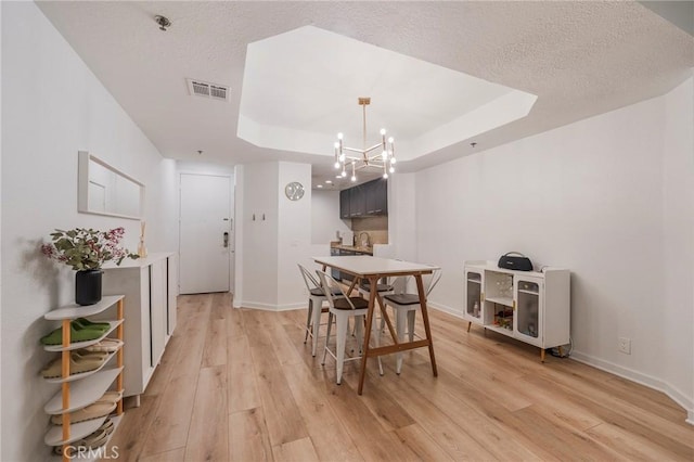 585 N Rossmore Ave Unit 209, Los Angeles, CA 90004 - dining room with light wood finished floors, a chandelier, a raised ceiling, a textured ceiling, and baseboards