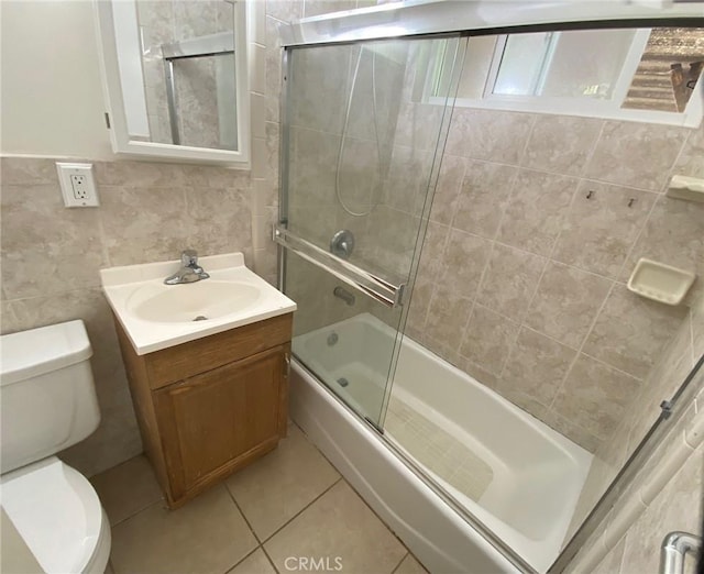 1017 W Prune Ave, Lompoc, CA 93436 - bathroom featuring toilet, vanity, bath / shower combo with glass door, tile walls, and tile patterned flooring