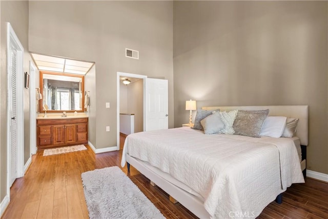 12531 Cluster Pines Rd, Garden Grove, CA 92845 - bedroom featuring a towering ceiling, baseboards, wood-type flooring, ensuite bath, and a sink