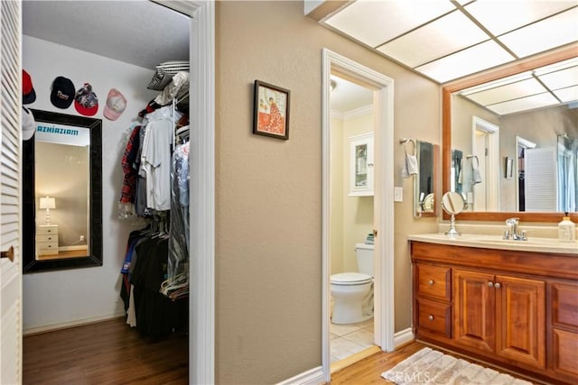 12531 Cluster Pines Rd, Garden Grove, CA 92845 - bathroom with wood finished floors, vanity, toilet, a spacious closet, and baseboards