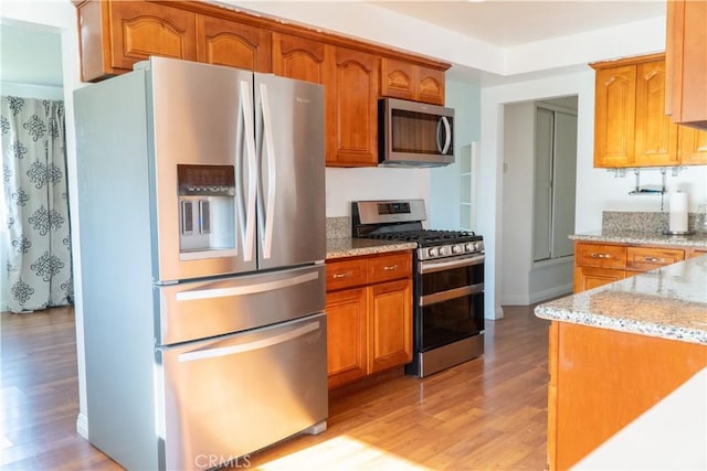 4865 Orchard St, Montclair, CA 91763 - kitchen with appliances with stainless steel finishes, light wood-style flooring, light stone countertops, and brown cabinetry