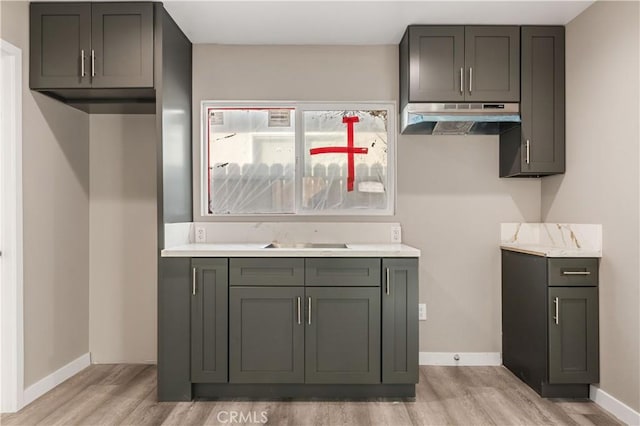 13250 Mercer St, Pacoima, CA 91331 - kitchen featuring under cabinet range hood, light wood-type flooring, baseboards, light countertops, and a sink
