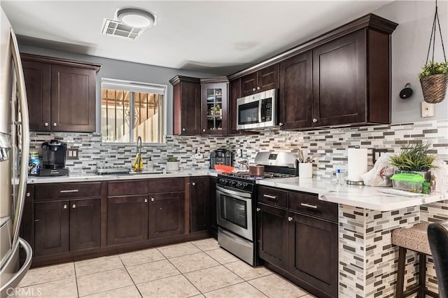 13250 Mercer St, Pacoima, CA 91331 - kitchen with stainless steel appliances, light countertops, backsplash, light tile patterned floors, and dark brown cabinetry