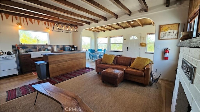 1240 Geronimo Trl, Yucca Valley, CA 92284 - living room featuring light wood-style floors, arched walkways, beam ceiling, and a fireplace
