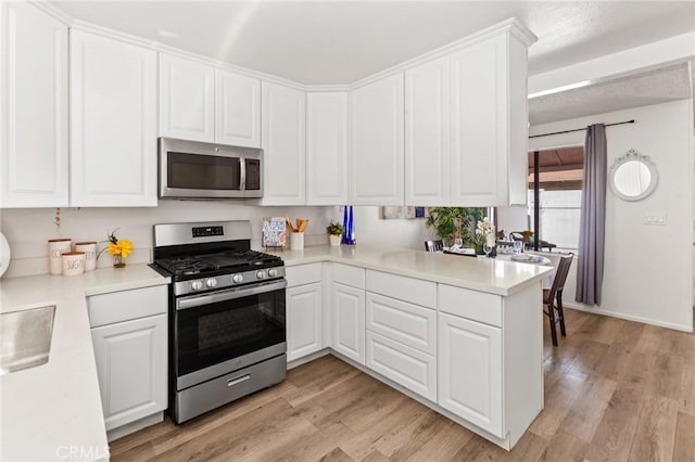 309 N Raitt St Unit C, Santa Ana, CA 92703 - kitchen with appliances with stainless steel finishes, white cabinets, light wood-style flooring, and light countertops