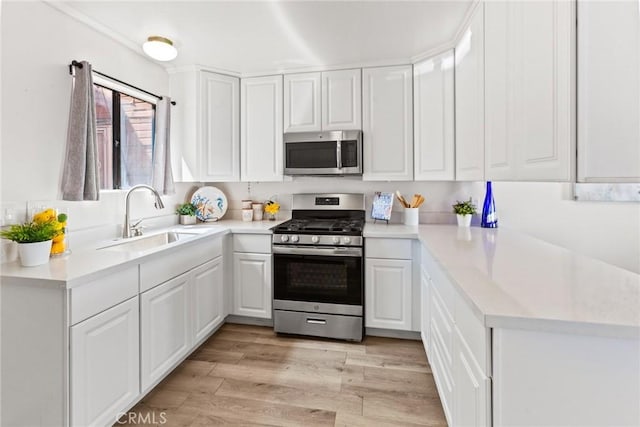 309 N Raitt St Unit C, Santa Ana, CA 92703 - kitchen with stainless steel appliances, a sink, white cabinetry, light countertops, and light wood-style flooring