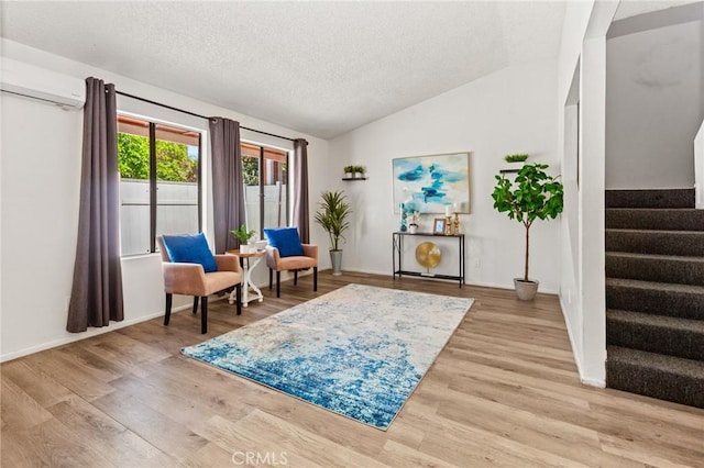 309 N Raitt St Unit C, Santa Ana, CA 92703 - sitting room featuring a wall mounted AC, lofted ceiling, stairway, a textured ceiling, and light wood-type flooring