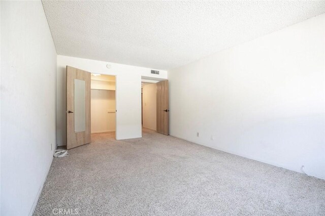 465 Ivy St Unit 203, Glendale, CA 91204 - unfurnished bedroom featuring light carpet, a spacious closet, a textured ceiling, and a closet