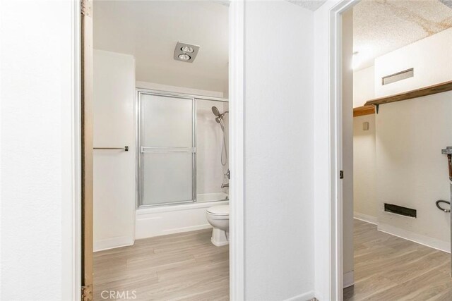 465 Ivy St Unit 203, Glendale, CA 91204 - full bath featuring toilet, wood finished floors, bath / shower combo with glass door, and baseboards
