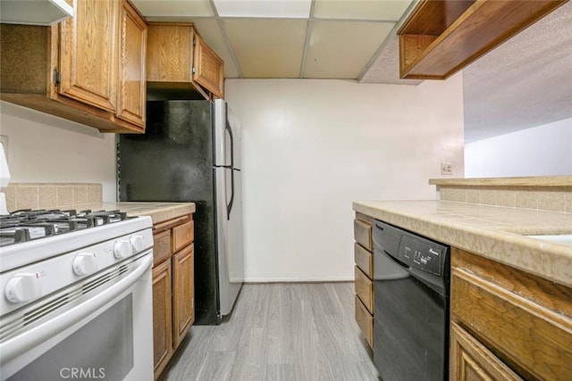 465 Ivy St Unit 203, Glendale, CA 91204 - kitchen with white gas range oven, black dishwasher, under cabinet range hood, a drop ceiling, and light wood-type flooring