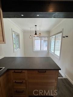 22425 Caminito Grande Unit 70, Laguna Hills, CA 92653 - kitchen featuring dark countertops, brown cabinets, a peninsula, ornamental molding, and baseboards