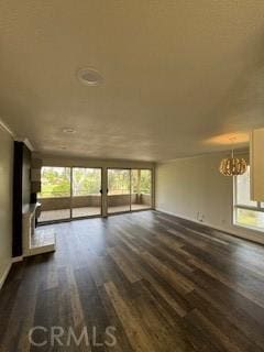 22425 Caminito Grande Unit 70, Laguna Hills, CA 92653 - unfurnished living room featuring dark wood finished floors, healthy amount of natural light, a chandelier, and baseboards