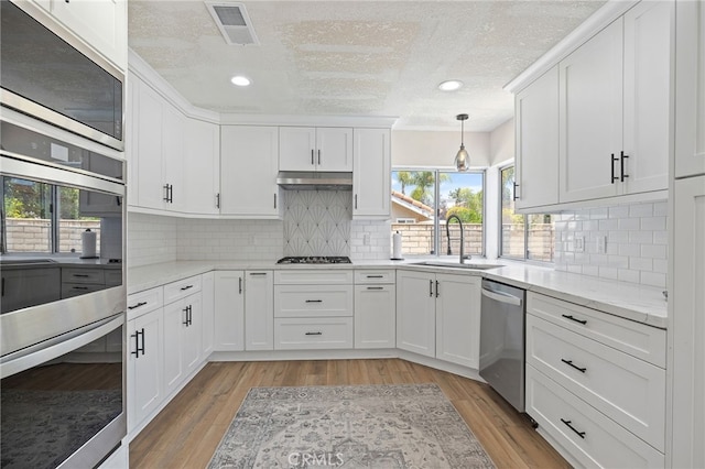 2251 Via Pacifica, Corona, CA 92882 - kitchen with a sink, appliances with stainless steel finishes, white cabinetry, a textured ceiling, and light wood-style flooring