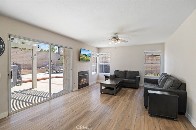 2251 Via Pacifica, Corona, CA 92882 - living area with light wood-style floors, a ceiling fan, baseboards, and a glass covered fireplace