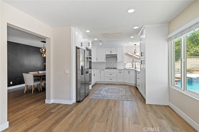 2251 Via Pacifica, Corona, CA 92882 - kitchen with appliances with stainless steel finishes, light wood-type flooring, white cabinets, baseboards, and backsplash