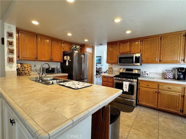 30027 Via Amante, Menifee, CA 92584 - kitchen featuring stainless steel appliances, a sink, a peninsula, recessed lighting, and brown cabinets