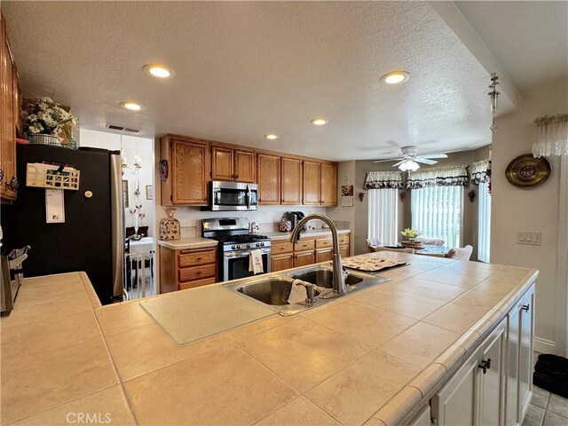 30027 Via Amante, Menifee, CA 92584 - kitchen featuring appliances with stainless steel finishes, a sink, tile counters, a textured ceiling, and recessed lighting