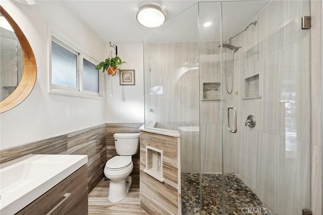 5226 Old Mill Rd, Riverside, CA 92504 - bathroom featuring tile walls, toilet, vanity, a stall shower, and a wainscoted wall
