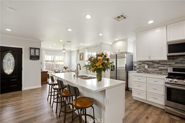 15952 Norcrest Dr, Whittier, CA 90604 - kitchen featuring stainless steel appliances, a sink, ornamental molding, tasteful backsplash, and white cabinets