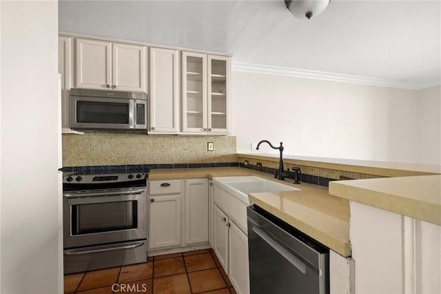 1187 E 3rd St Unit 104, Long Beach, CA 90802 - kitchen featuring appliances with stainless steel finishes, a sink, backsplash, ornamental molding, and glass insert cabinets