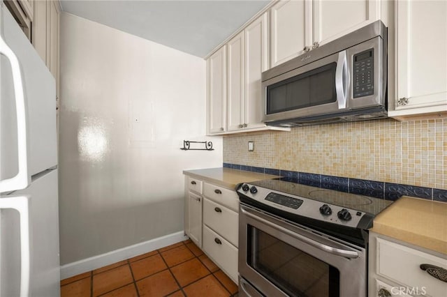 1187 E 3rd St Unit 104, Long Beach, CA 90802 - kitchen with appliances with stainless steel finishes, baseboards, tasteful backsplash, light tile patterned floors, and white cabinetry