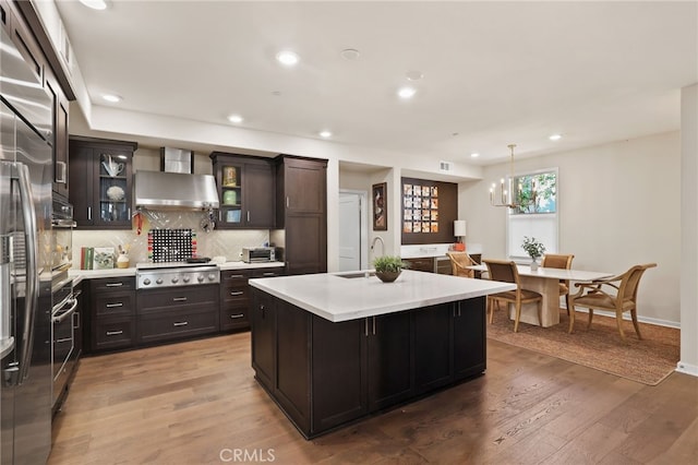 223 Carlow, Irvine, CA 92618 - kitchen with wall chimney range hood, stainless steel appliances, light countertops, decorative backsplash, and a kitchen island with sink