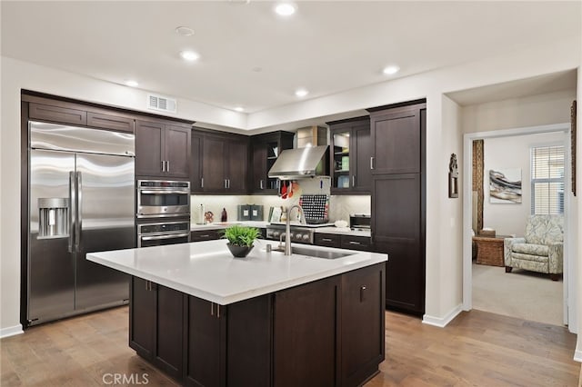 223 Carlow, Irvine, CA 92618 - kitchen featuring stainless steel appliances, wall chimney exhaust hood, dark brown cabinets, light countertops, and a sink