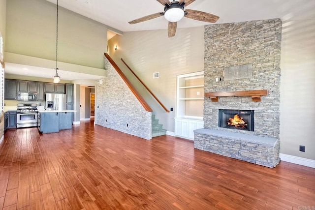 3313 Dehesa Rd Unit 85, El Cajon, CA 92019 - unfurnished living room featuring high vaulted ceiling, a ceiling fan, stairway, dark wood-type flooring, and a stone fireplace