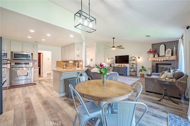1266 Panorama Point Ct, Merced, CA 95340 - dining room with light wood finished floors, ceiling fan, recessed lighting, and a fireplace