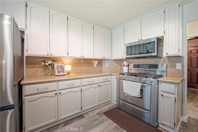 1266 Panorama Point Ct, Merced, CA 95340 - kitchen with appliances with stainless steel finishes, light wood-style flooring, light countertops, white cabinetry, and tasteful backsplash