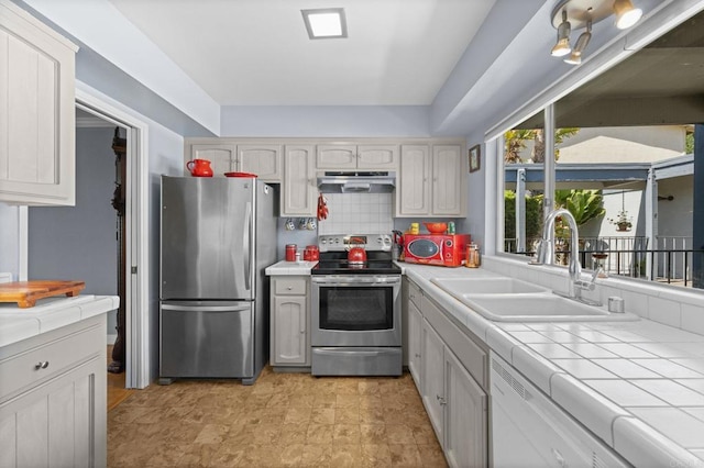3612 Vista Bella Unit 5, Oceanside, CA 92057 - kitchen featuring stainless steel appliances, under cabinet range hood, a sink, tile counters, and backsplash