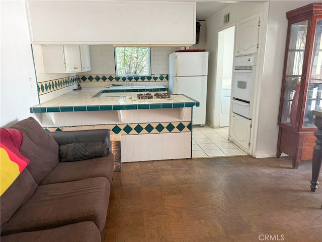 3401 Millbury Ave, Baldwin Park, CA 91706 - kitchen with tile countertops, white appliances, a peninsula, tasteful backsplash, and white cabinetry