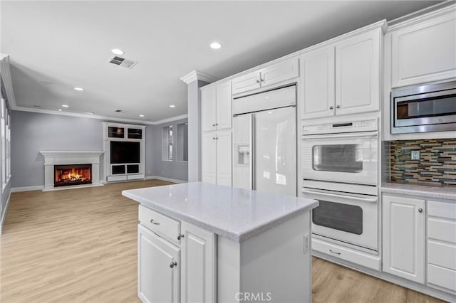 23922 Lakeside Rd, Valencia, CA 91355 - kitchen featuring built in appliances, crown molding, backsplash, light wood finished floors, and white cabinets