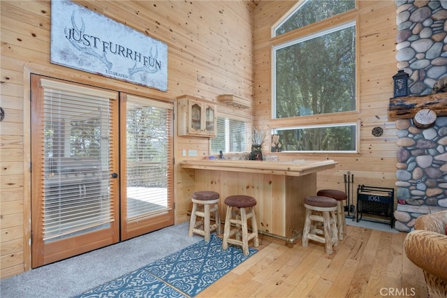 10820 Bonita Way, Wofford Heights, CA 93285 - kitchen featuring wood walls, a high ceiling, light wood-style flooring, plenty of natural light, and a kitchen breakfast bar