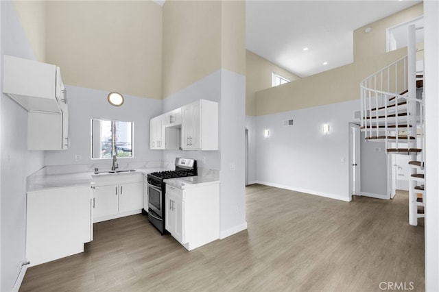 4406 Cahuenga Blvd, Toluca Lake, CA 91602 - kitchen featuring stainless steel gas stove, a high ceiling, a sink, plenty of natural light, and light countertops