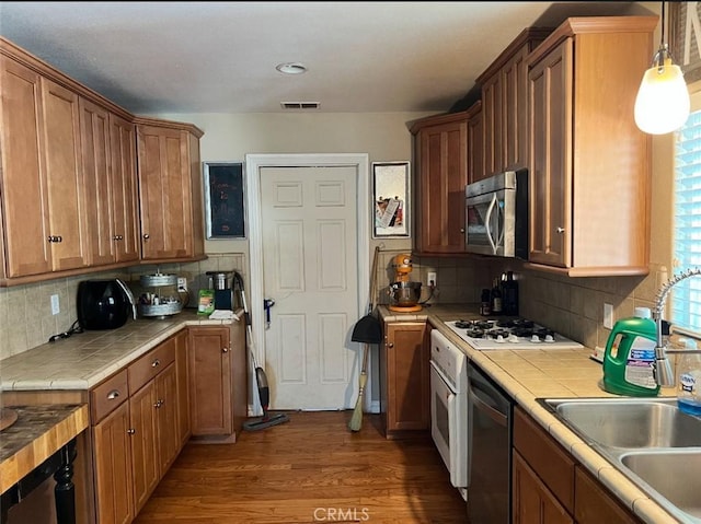 619 C St, Lemoore, CA 93245 - kitchen with appliances with stainless steel finishes, tile countertops, wood finished floors, a sink, and tasteful backsplash