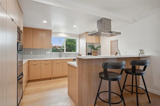 4920 Island View St, Oxnard, CA 93035 - kitchen with extractor fan, a kitchen bar, a peninsula, light brown cabinetry, and backsplash