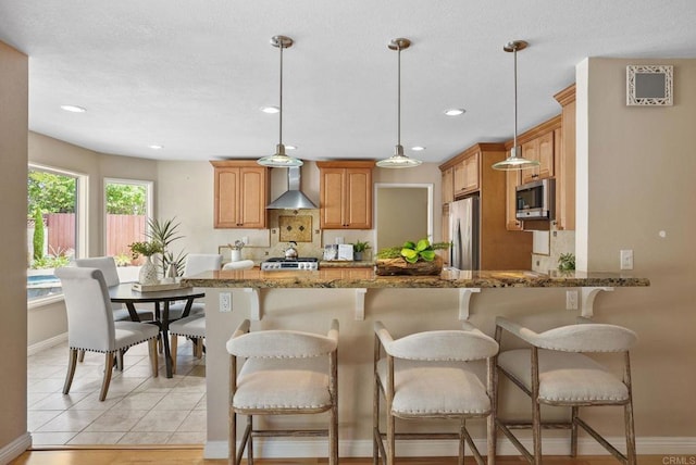 3442 Celinda Dr, Carlsbad, CA 92008 - kitchen featuring appliances with stainless steel finishes, wall chimney range hood, stone countertops, a peninsula, and pendant lighting